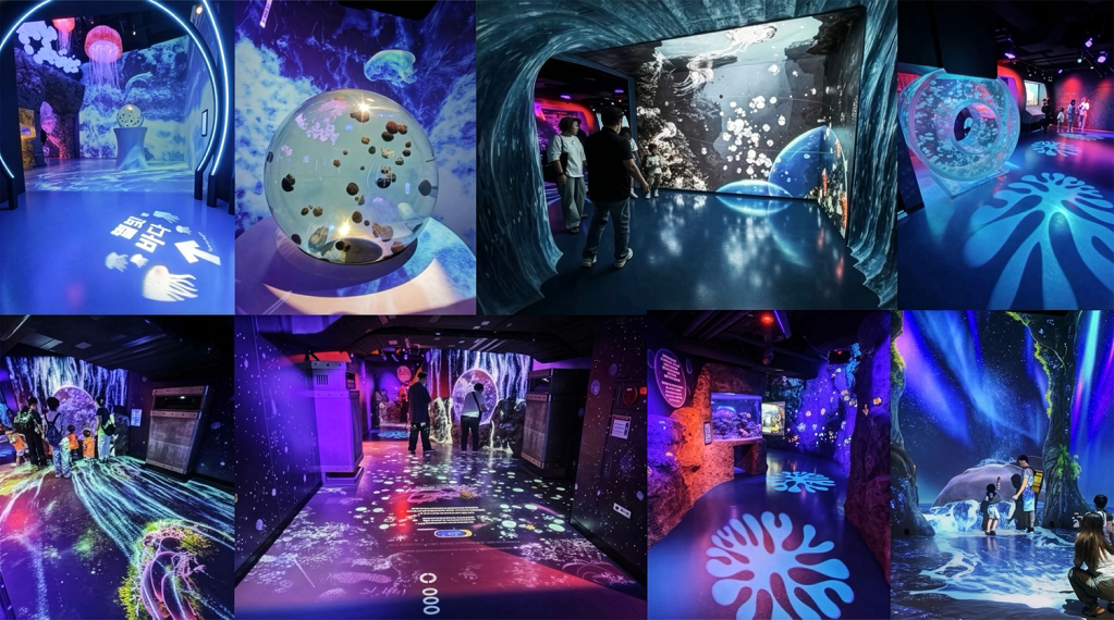 An immersive exhibit featuring colorful water-themed projections and jellyfish displays in a darkened room. Visitors explore interactive installations with illuminated floors and walls showcasing marine life imagery.